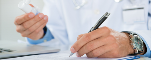 Image of a pharmacists taking notes and holding medication sourced from Canva.com